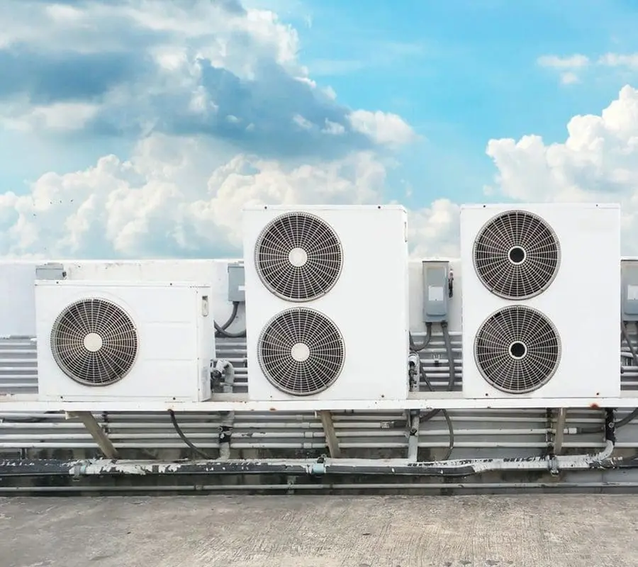 A row of air conditioners sitting on top of a building.