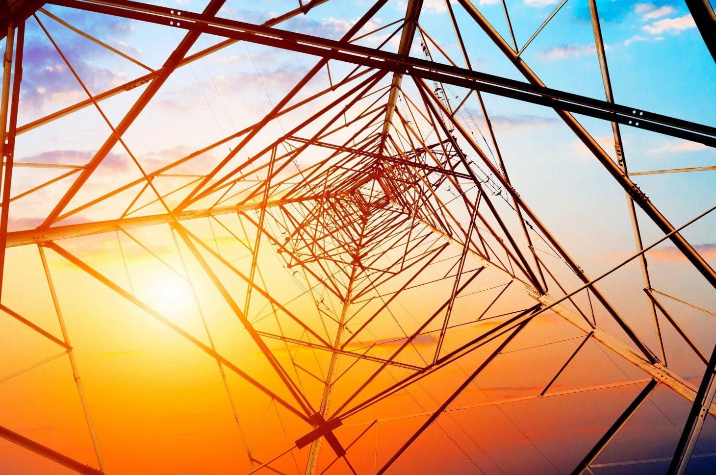 A view of an electrical tower with the sun setting behind it.