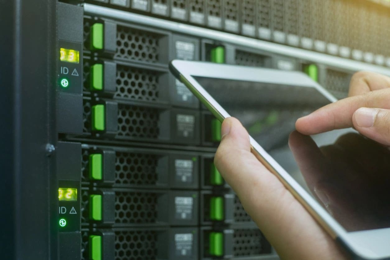 A person holding a tablet in front of some servers.