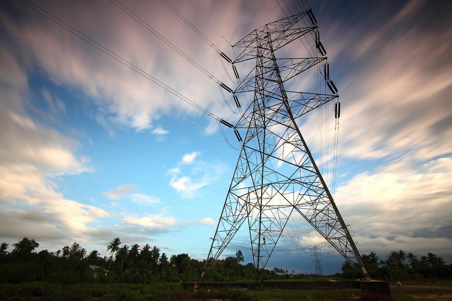 A tall power tower with trees in the background