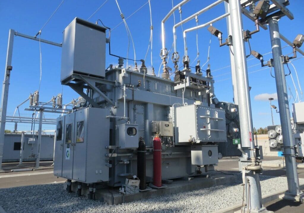 A large electrical power transformer on top of gravel.